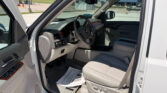 Open car door reveals the beige interior of a Chevrolet SUV, steering wheel and dashboard in view with a gas station outside the window.