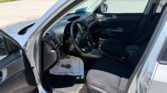 Interior of a silver SUV with the driver's-side door open, showing the steering wheel, dashboard, and center console; parking lot outside.