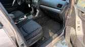 Interior of a car showing the driver's seat, steering wheel, center console, and a can and papers on the floor beside the gear shifter.
