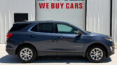 Dark blue Chevrolet Equinox parked in front of a white industrial building with a red WE BUY CARS sign on the garage door behind it.