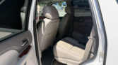 Open rear passenger door showing beige leather back seats and door panel inside a white SUV, parked in a lot.