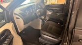 Interior of a vehicle cabin viewed from the open driver’s side door, showing the dashboard, steering wheel, and front seats