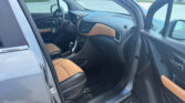 Interior of a gray SUV with brown leather seats and the driver’s door ajar, showing the steering wheel and center console with a touchscreen unlocked in a parking lot.