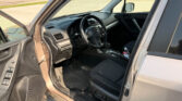 Interior of a car with the driver's door open, showing the steering wheel, dashboard, and center console; gas station lot visible outside.