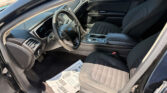 View of a Ford car’s black interior from the driver’s side, showing the steering wheel, dashboard, center console, and papers on the floor.