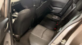Rear passenger area of a dark car with black fabric seats, visible seat belts, and front seats ahead.