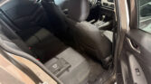 Interior of a dark sedan seen from the rear passenger door, showing the front seats, center console, and dashboard with steering wheel visible.