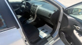 Interior of a silver car with the driver’s door open; steering wheel, dashboard, and gear shift visible.