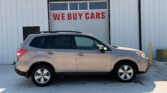 Silver SUV parked in front of a white industrial building with a large garage door reading 'WE BUY CARS' in red letters