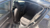 Open rear door showing the dark fabric interior of a sedan, with front seats and headrests visible.