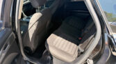 Back seat area of a black car with fabric seats and visible headrests, viewed from the open rear door.** concisely describes interior.