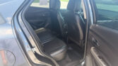 Rear passenger area of a dark car with black leather seats and headrests, viewed from the open back door.