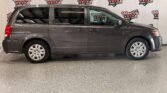 Side view of a gray minivan indoors, with a Wheel City Auto Finance Centers banner in the background.
