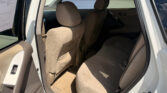 Open rear passenger door of a beige car, showing the back seat with headrests and seat belts visible.