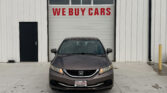 Front view of a gray Honda parked in front of a white garage door with 'WE BUY CARS' in red letters loping across the door.