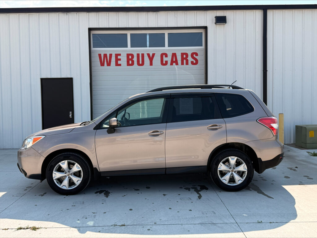 Silver SUV parked in front of a white industrial building with a garage door that reads 'WE BUY CARS'.