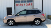 Silver SUV parked in front of a white industrial building with a garage door that reads 'WE BUY CARS'.