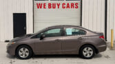 Gray sedan parked in front of a building with a large white garage door that reads 'WE BUY CARS'.