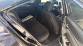 Rear passenger-side door open, showing black cloth back seat and front seats with steering wheel visible in a car interior