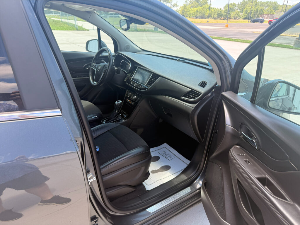 Open driver-side door of a gray Buick SUV, revealing black leather seats and dashboard interior.