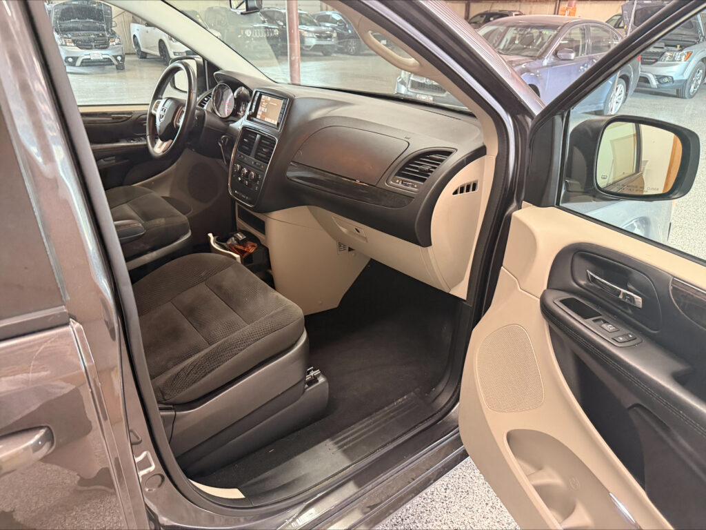 Interior of a vehicle showing the front passenger area with steering wheel, center touchscreen, and beige/black dash panel