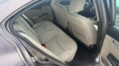 Rear seating area of a beige sedan with the back door open, showing the beige fabric seats and headrests.