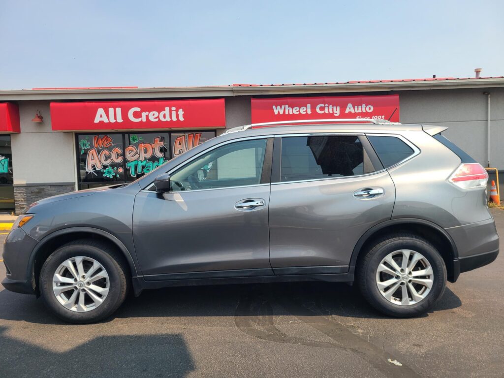Silver SUV parked in front of a red storefront with All Credit and Wheel City Auto signs.