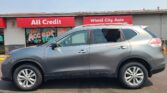 Silver SUV parked in front of a red storefront with All Credit and Wheel City Auto signs.