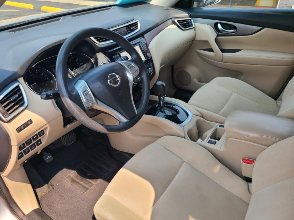 Beige car interior with steering wheel, center console, and front seats visible from the driver’s side