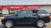 Front of a storefront with red signs reading 'All Credit' and 'Wheel City Auto', and a dark SUV parked in front.