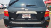 Rear view of a dark gray Toyota Highlander SUV in a parking lot, showing the tail lights, rear window wiper, and Wheel City license plate frame.
