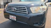 Front view of a dark blue Toyota vehicle at Wheel City Auto Finance Centers dealership, with a red 'City Auto Since 1993' awning in the background