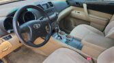 Beige Toyota car interior with steering wheel, dashboard, center console, gear shifter, and cupholders visible between front seats.