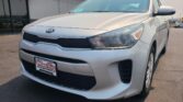 Front-left view of a white Kia sedan at a car dealership, Wheel City Auto Finance Centers license plate frame visible in the foreground.