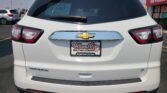 Rear view of a white Chevrolet Traverse LT at a car dealership, showing the Wheel City Auto Finance Centers plate frame and a 'We Finance' sign on the side window.