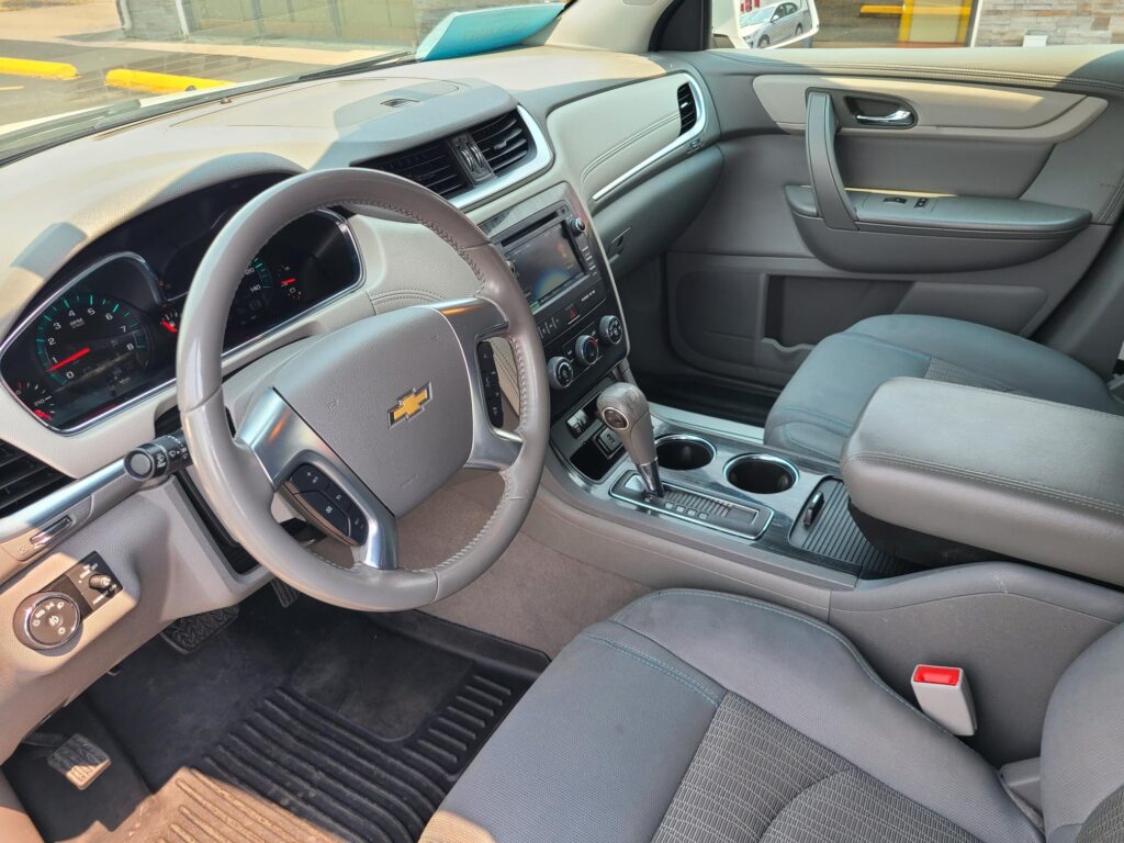 Interior view of a car cabin showing the steering wheel, dashboard with infotainment screen, center console, and front seats.