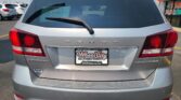 Rear view of a silver Dodge Journey in a car dealership lot, with a D-1467 window sticker and Wheel City plate frame visible on the license plate area.