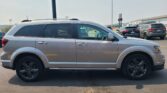 Silver SUV parked in a lot, shown in profile with other vehicles and a warehouse in the distance.