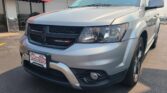 Close-up of the front end of a silver Dodge SUV at a car dealership, Wheel City Auto visible on the storefront sign and license plate frame.