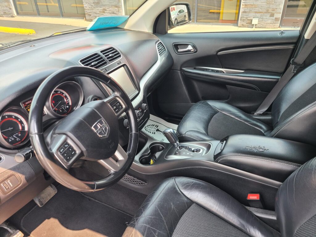 Front interior of a black SUV: steering wheel, dashboard, center console, and leather seats visible from the passenger seat angle.