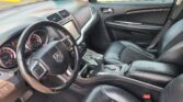 Front interior of a black SUV: steering wheel, dashboard, center console, and leather seats visible from the passenger seat angle.