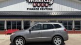 Silver SUV parked in front of Wheel City Auto Finance Centers storefront with large sign and a red bench nearby.