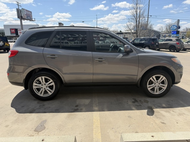 Gray crossover SUV seen in profile, parked in a lot with other vehicles and clear blue sky above.