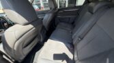 Rear seating area of a SUV with three gray fabric seats, headrests, and seatbelts; front seats visible.