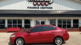 Red sedan parked in front of the Wheel City Auto Finance Centers storefront.