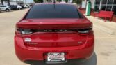 Rear view of a red Dodge Dart SXT parked in a dealership lot; black taillight bar with DODGE across, DART and SXT badges, Wheel City license plate frame.