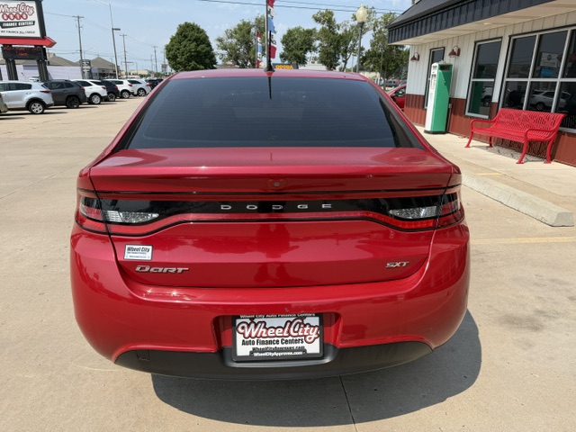 Rear view of a red Dodge Dart SXT parked in a dealership lot; black taillight bar with DODGE across, DART and SXT badges, Wheel City license plate frame.