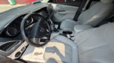 Interior view of a gray car: steering wheel, center console with gear shifter, and front seats visible in daylight