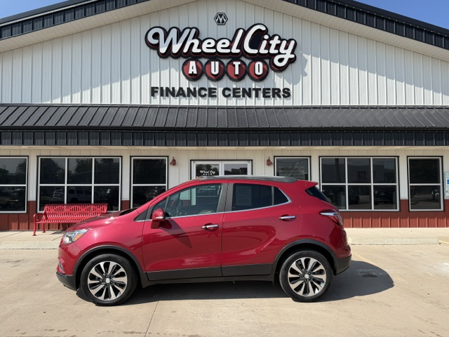 Red compact SUV parked in front of Wheel City Auto Finance Centers storefront, with the dealership sign visible.