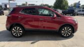 Side view of a red compact SUV parked in a car dealership lot on a sunny day.